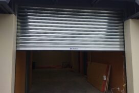 A technician removing an old roller door and installing a new motorised roller door, ensuring proper alignment and secure mounting of the new door and motor system.